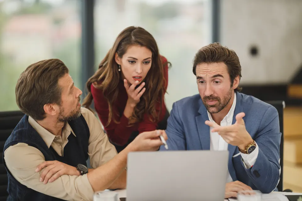 Colleagues gathered around a laptop discussing a process