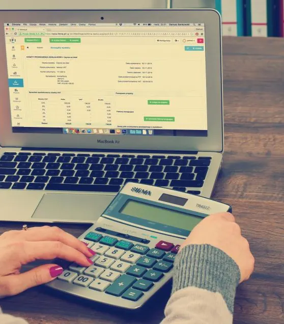 Payroll figures being checked on a laptop with a calculator beside it