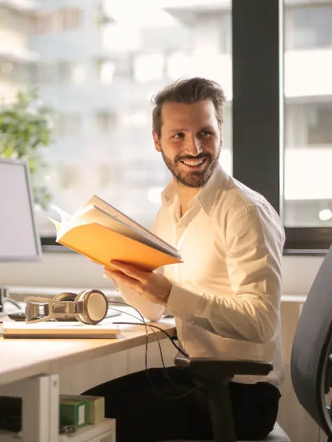 Smiling office worker reviewing documents at his desk